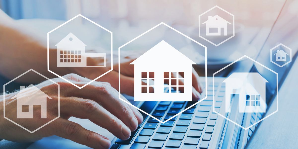 Hands typing on a laptop keyboard with overlay icons of house symbols, representing real estate technology.