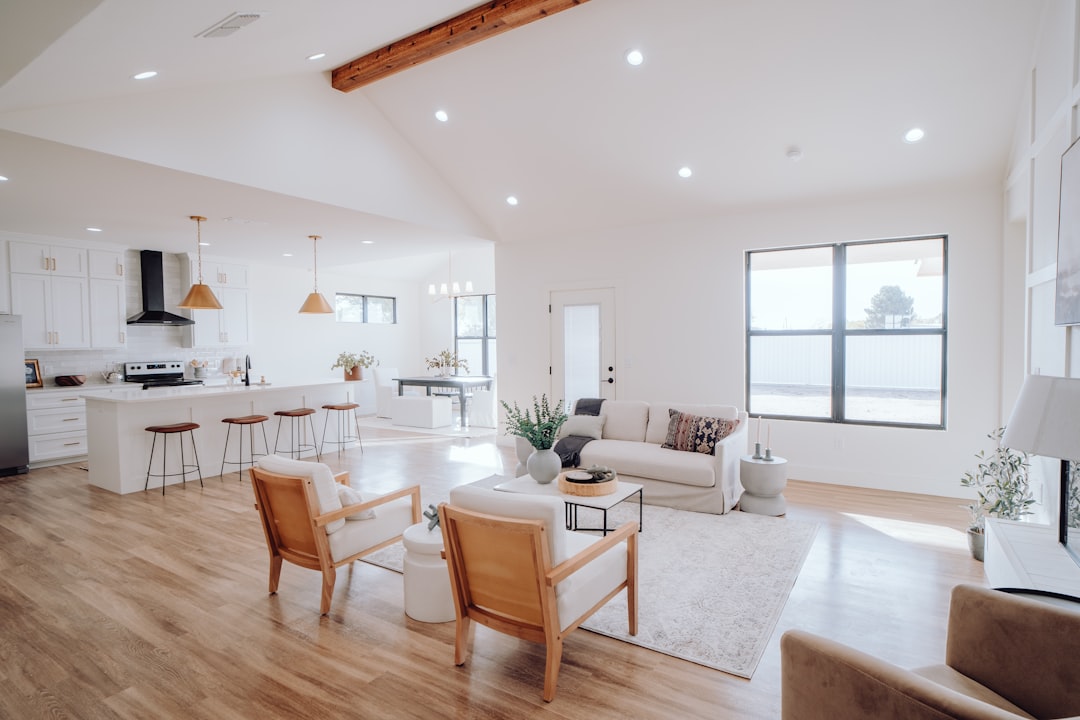 A person carefully reviewing architectural blueprints inside a sunlit, modern home, representing the thoughtful decision-making involved in real estate.